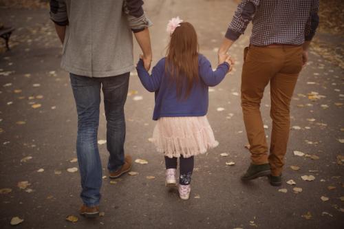 Two men holding hands with a little girl.